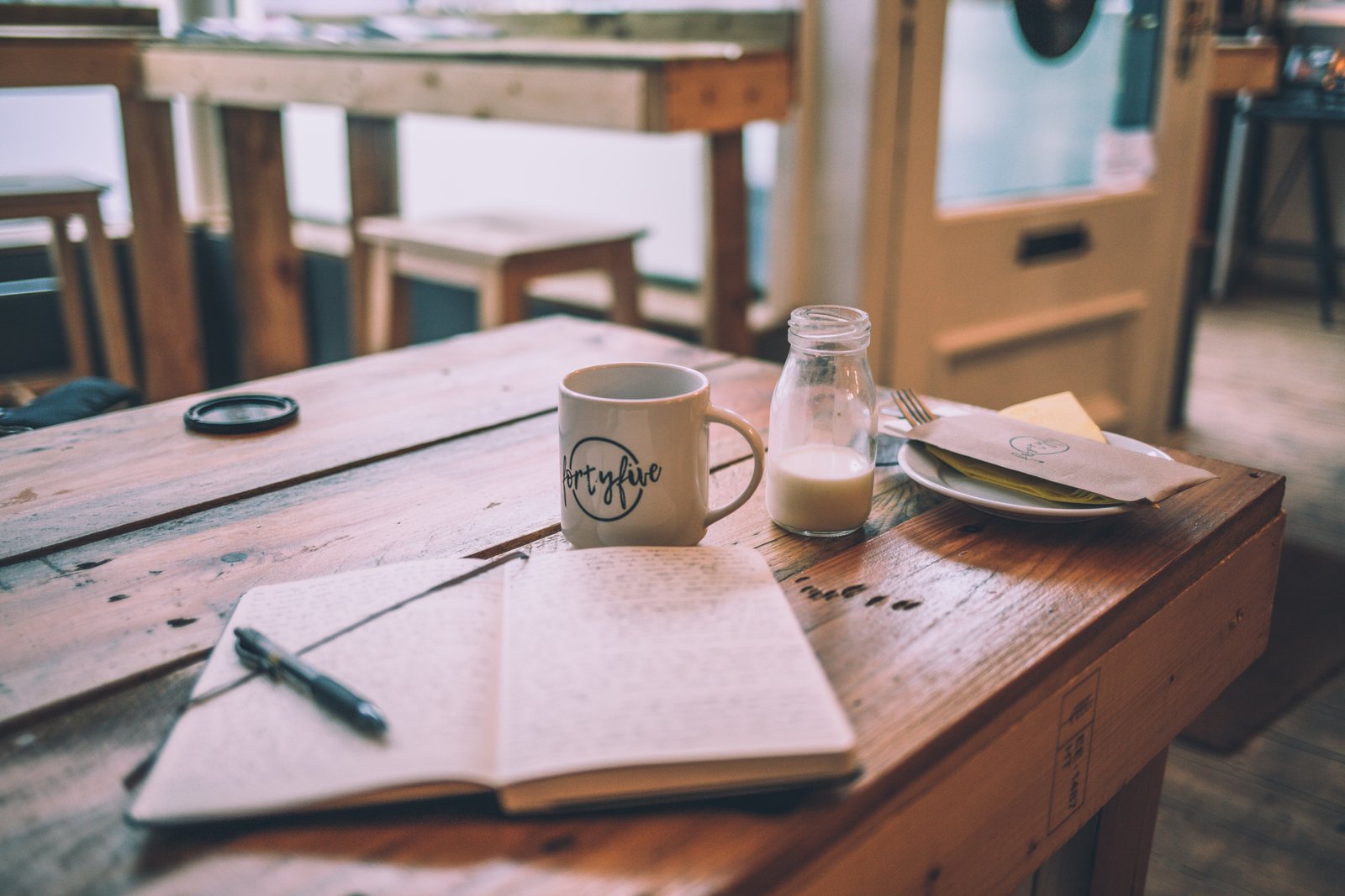 carnet pour écrire avec un stylo sur une table en bois avec une tasse de café